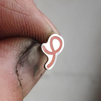 Twist Doodle Stud in Coral-pink held between fingers of the maker